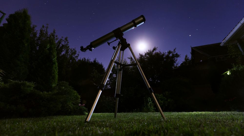 Débutant penché sur un télescope à la tombée de la nuit, à l'heure des premières erreurs de réglage d'un télescope débutant