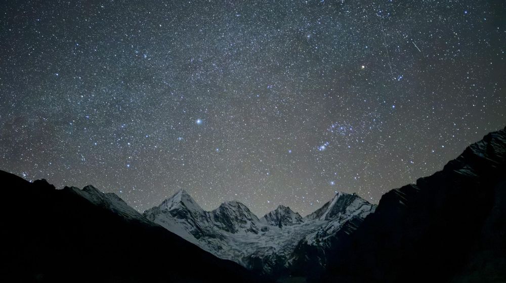 Livre ouvert posé sous un ciel étoilé, pour choisir un livre pour observer les étoiles